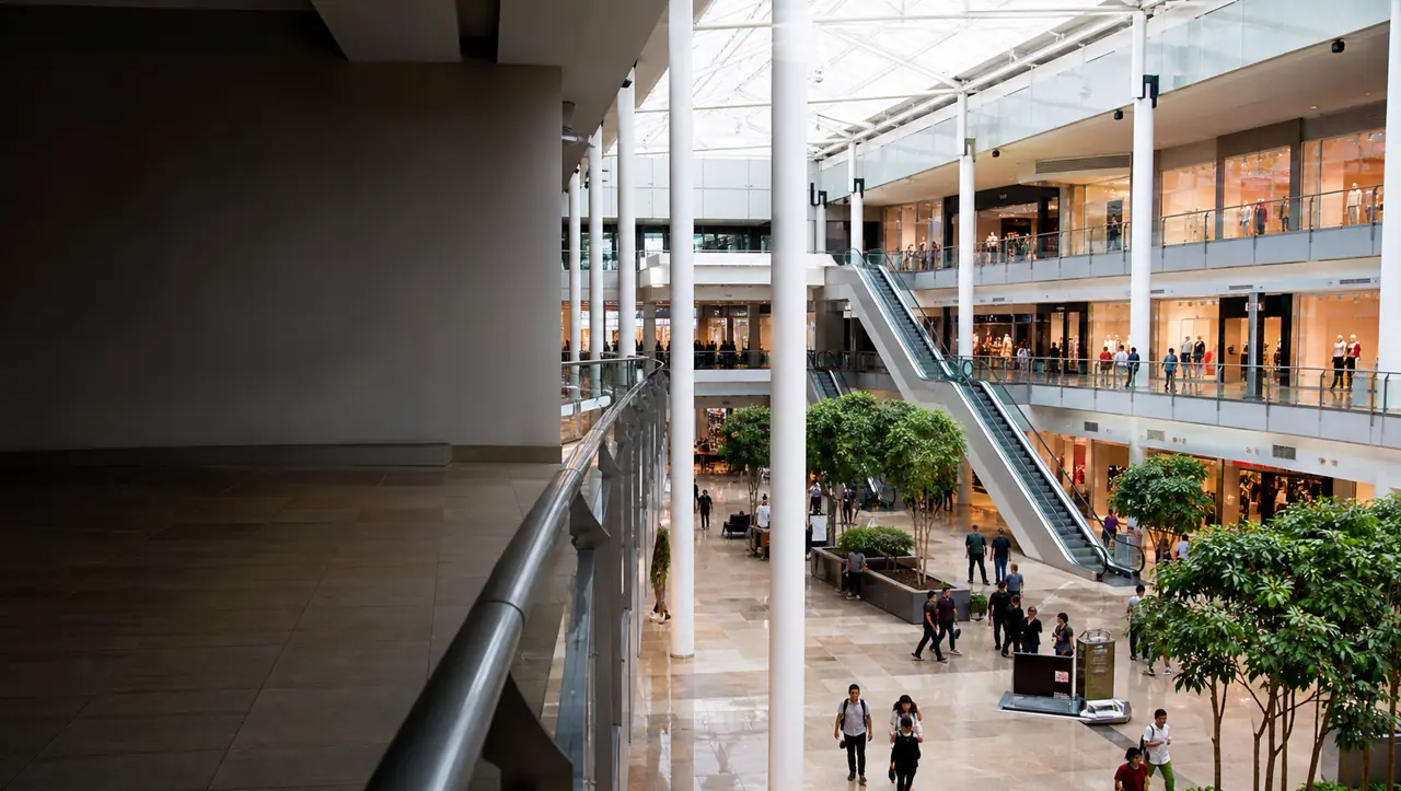 Atrio de un centro comercial moderno con locales, escaleras mecánicas y visitantes